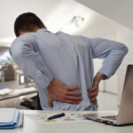 man sitting at desk with lower back pain Massage Therapy for back pain in Tampa Bay