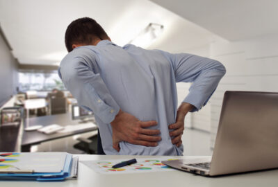 man sitting at desk with lower back pain Massage Therapy for back pain in Tampa Bay